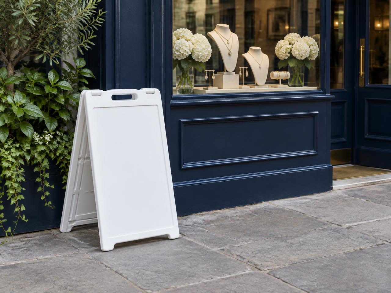 A white sidewalk board outside a blue jewelry storefront